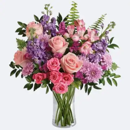 A professional roses and gerbera arrangement in a woven basket featuring pink blossoms and white lilies.