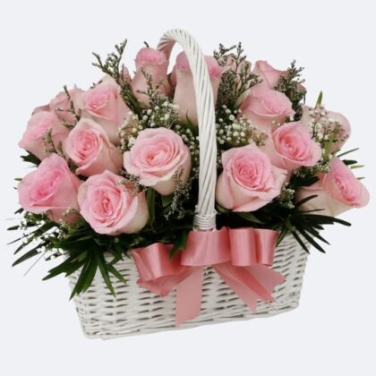 A fresh pink rose arrangement in basket decorated with a satin ribbon and white baby's breath flowers.