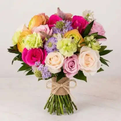 A stunning ranunculus and roses bouquet featuring soft pastel petals and lush greenery in a professional arrangement.