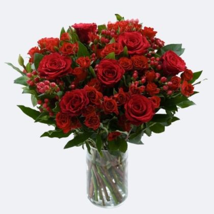 A dense red roses bouquet flowers arrangement with hot pink accents and mint leaves in a green gift box.