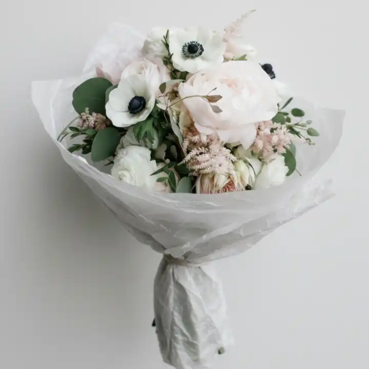 White Anemone and Peony Silk-Wrapped Bouquet 1 Hand-tied anemone and peony bouquet wrapped in white textured paper with fresh greenery and rustic twine.