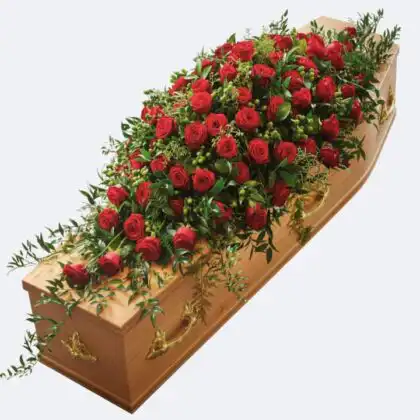 Natural fresh red roses arranged as a funeral spray for coffin with green foliage.