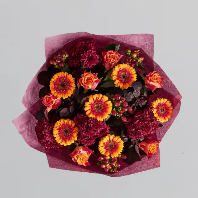 Autumn rose and gerbera hand tied 1 A cheerful Gerbera and Rose Bouquet with orange Gerbera daisies and deep red roses accented by fall leaves and hypericum berries.