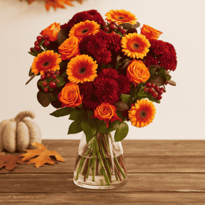 A beautiful arrangement featuring an orange Autumn Rose and Gerbera Vase design, including yellow and white daisies, displayed in a bright orange gift box.