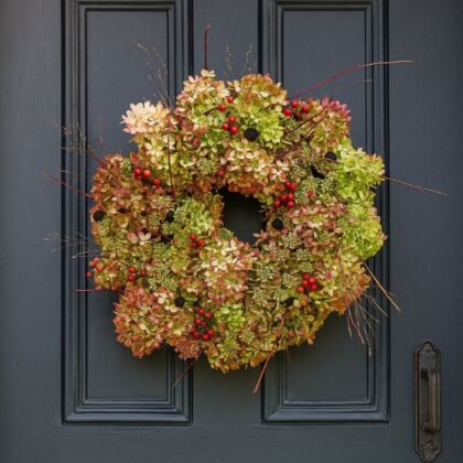 A beautifully natural luxury Christmas wreath for a front door, made from dried hydrangea flowers, red berries, and delicate twigs, hanging on a dark gray door. Luxury Christmas Wreaths For Front Door for sales