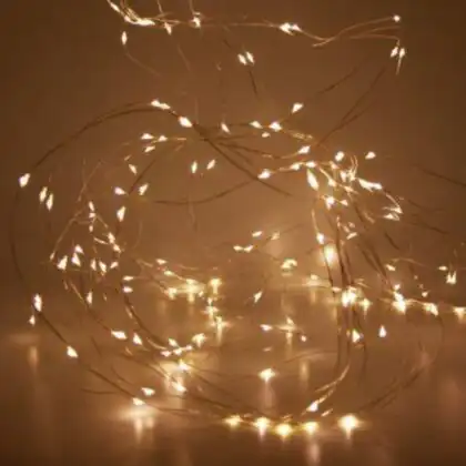 A close-up of a glowing bundle of flexible LED micro wire Christmas lights on a thin copper-coloured wire.