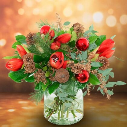 A vibrant Christmas vase arrangement with red tulips, shiny baubles, pine cones, and green foliage, available for delivery Christmas Eve. Decorative Christmas flowers for sale