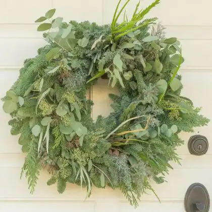 A highly detailed, oversized Large Christmas Ramble Wreath featuring a mix of forest greenery, pinecones, and red ribbon, perfect for outdoor display.