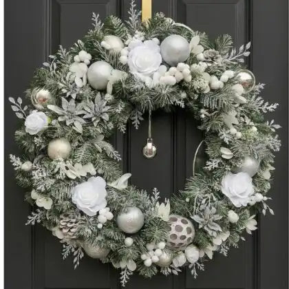 A high-end, sparkling Luxury winter frost Christmas wreath featuring frosted silver pine needles, white berries, and delicate crystal accents, displayed on a dark surface.