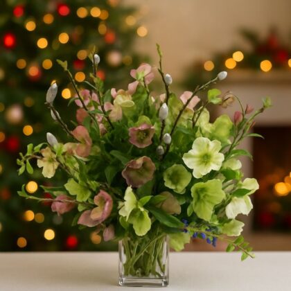 A luxurious bouquet of mixed pink and green Hellebores and willow twigs arranged as christmas decorations in a glass vase.