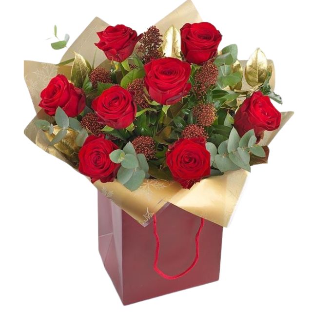 Blog 12 Vibrant red rose Christmas fresh flower arrangement with golden foliage and dried accents, beautifully packaged in a festive red gift bag. Christmas fresh flower arrangements For sale