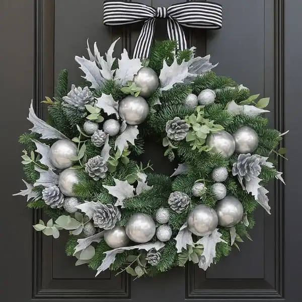 Silver and White Christmas wreath 1 An elegant and contemporary Silver and White Christmas wreath decorated with glittery ornaments, metallic ribbon, and frosted leaves, hanging on a minimalist door.
