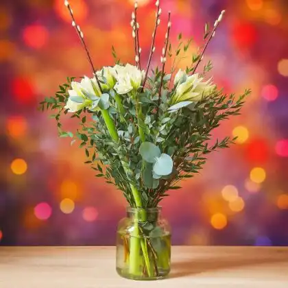 A beautiful white flower arrangements for Christmas featuring Amaryllis blooms, green eucalyptus, and natural willow sticks in a clear glass vase. White Amaryllis Bouquet for sale