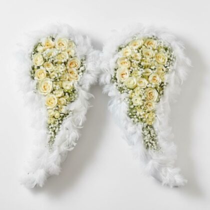 Fresh white rose and gypsophila angel wings funeral flowers with soft feather borders for a memorial service.
