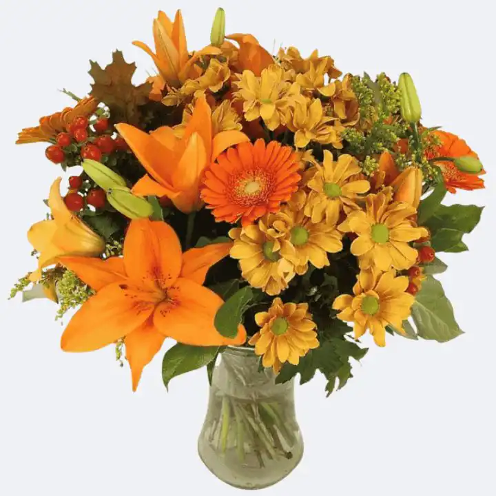 Vibrant Autumn Flower Vase Arrangement 1 Vibrant Autumn vase arrangement featuring sunflowers, orange roses, and deep red foliage in a clear glass vessel.