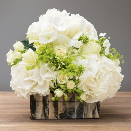 Luxury white hydrangea arrangements with cream roses and green bupleurum in a marble patterned box.
